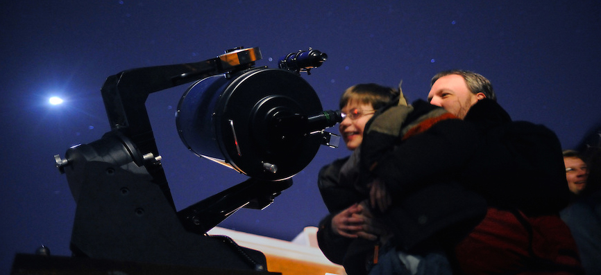 child looking through a telescope